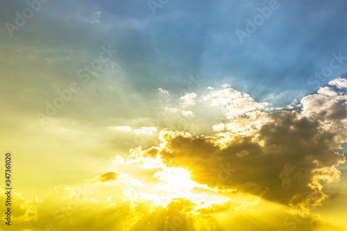 Bright sun in blue sky with yellow and green light and clouds