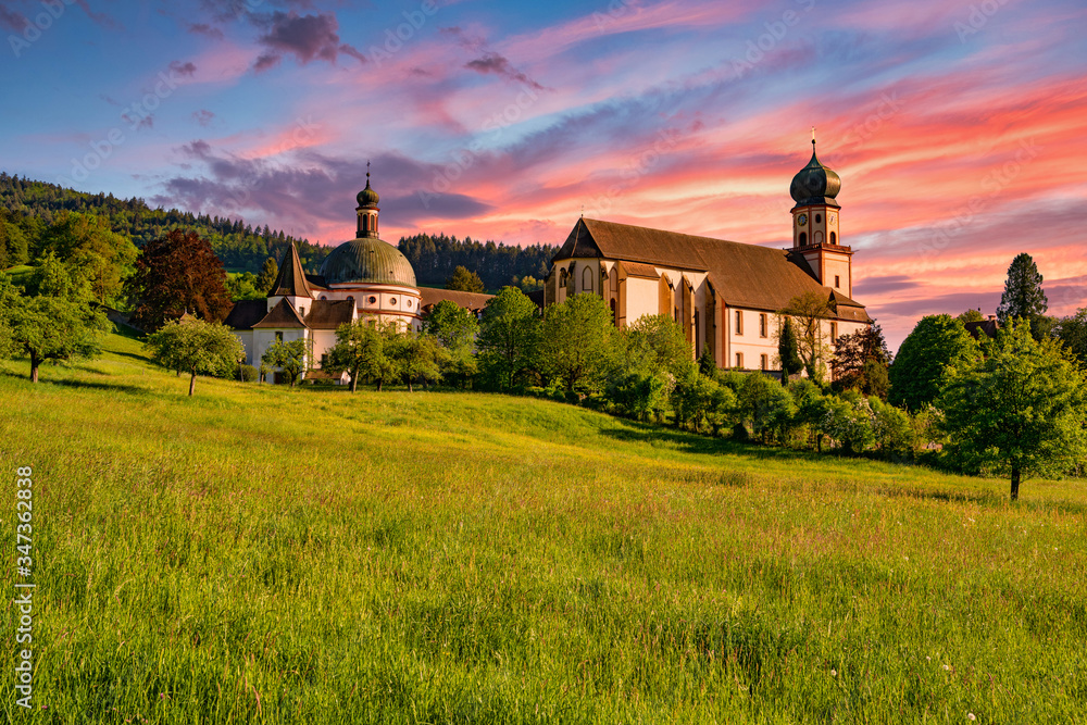 The Benedictine monastery St. Trudpert (Kloster Sankt Trudpert) in the Black Forest in Muenstertal at sunset in front of a colourful sky - obrazy, fototapety, plakaty 