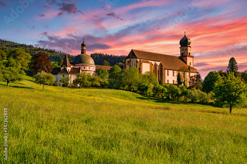 The Benedictine monastery St. Trudpert (Kloster Sankt Trudpert) in the Black Forest in Muenstertal at sunset in front of a colourful sky photo
