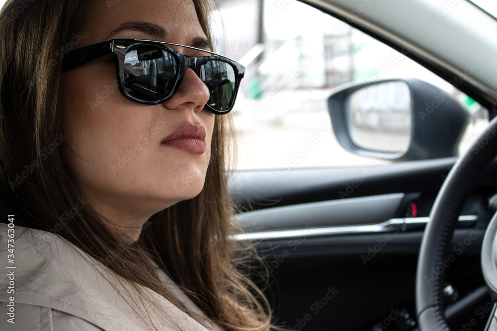 Portrait of a young brown-haired beautiful girl with green eyes and a light trench in the car Portrait of a young brown-haired beautiful girl with green eyes and a light trench in the car