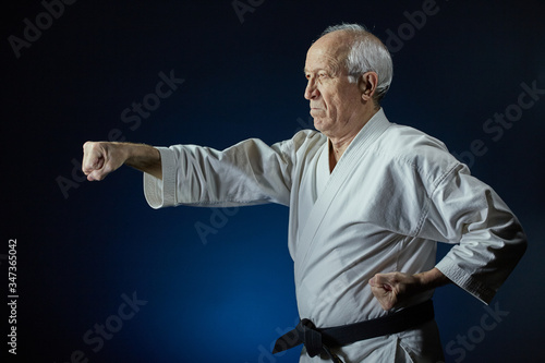 On a blue background, an old man athlete beats a punch arm