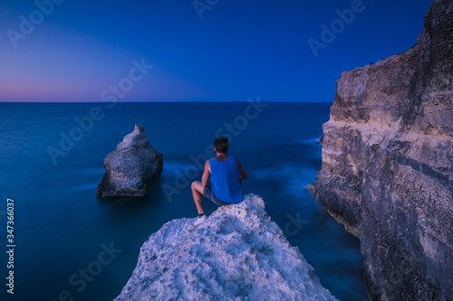 A man sitting on a rock in front of the sea