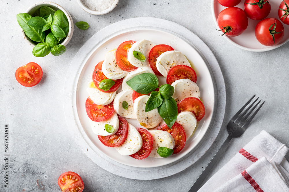 Italian caprese salad with sliced tomatoes, mozzarella, basil, olive oil on a light background. Top view. Italian caprese salad with sliced tomatoes, mozzarella, basil, olive oil on a light background. Top view.
