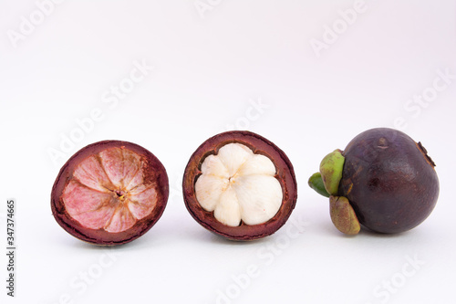 Half of the mangosteen fruit and one mangosteen placed side by side on a white ground.