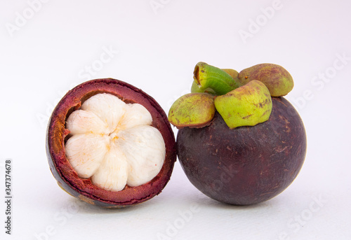 Half of the mangosteen fruit and one mangosteen placed side by side on a white ground.