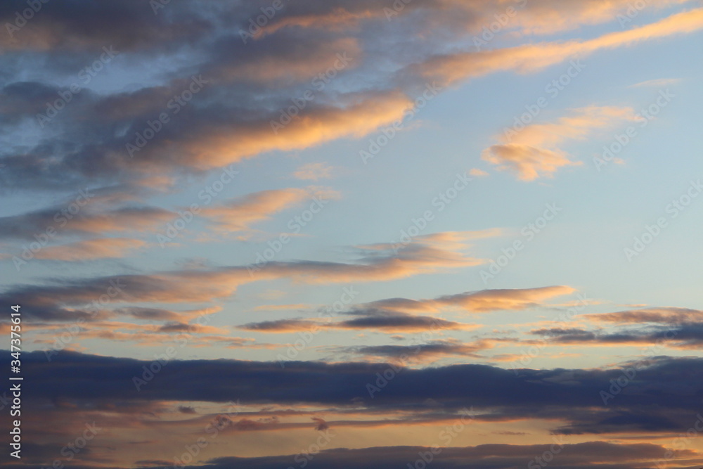 Clouds in the sky are illuminated from below by the red light of the sun. Sunset or sunrise scene at dusk. Clouds in the sky are illuminated from below by the red light of the sun. Sunset or sunrise scene at dusk.