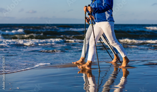 Fotografie, Obraz Nordic walking - two women working out on beach