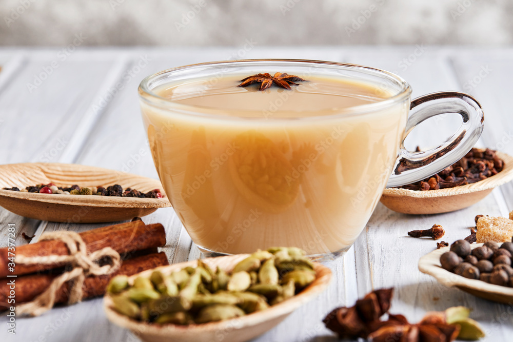Traditional Indian drink - masala tea with spices. Cinnamon, cardamom, anise, sugar, cloves, pepper on a light wooden background. Traditional Indian drink - masala tea with spices. Cinnamon, cardamom, anise, sugar, cloves, pepper on a light wooden background.