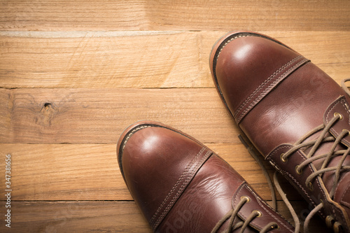 ฺBrown leather shoes with vintage camera on a wooden floor.Brown vintage leather boots aligned selective focus.Men leather shoes  © sek_gt
