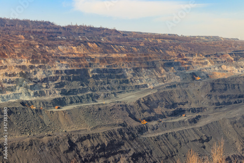 Huge iron ore quarry with working dump trucks and excavators © olyasolodenko