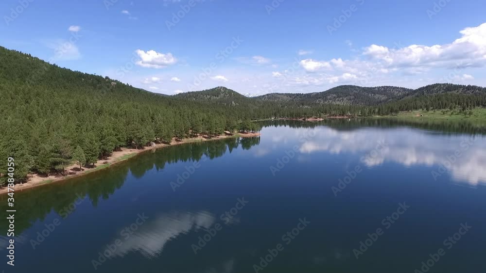 Aerial view of beautiful calm lake by trees in forest against blue sky, reflection of clouds on water during sunny day - Lake Wellington, Colorado Aerial view of beautiful calm lake by trees in forest against blue sky, reflection of clouds on water during sunny day - Lake Wellington, Colorado