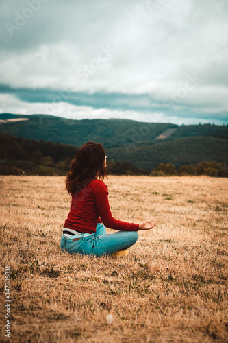 young woman doing yoga in a field in the hills