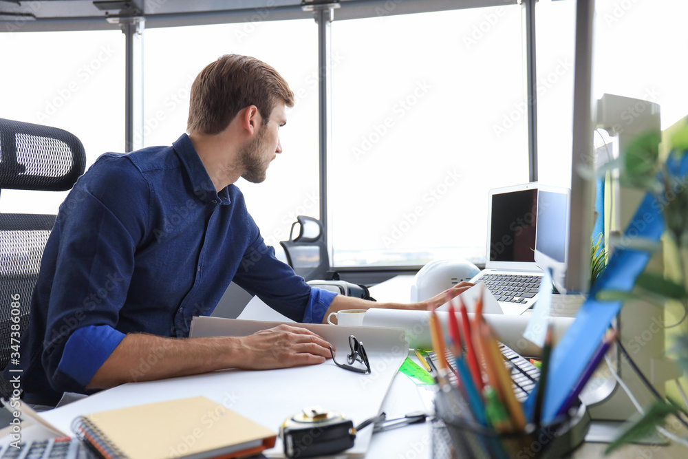 Shot of a handsome male architect working on a design in his office. Shot of a handsome male architect working on a design in his office.
