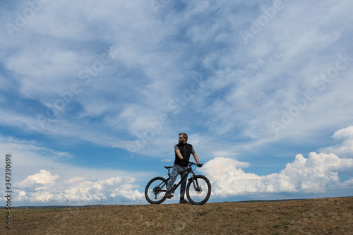 Sports brutal bearded guy on a modern mountain bike. A cyclist in a salt deserted place by the lake. © Mountains Hunter