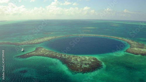 Aerial: Yacht near sinkhole against sky on sunny day, scenic view of seascape while drone panning from left to right - Great Blue Hole, Belize photo