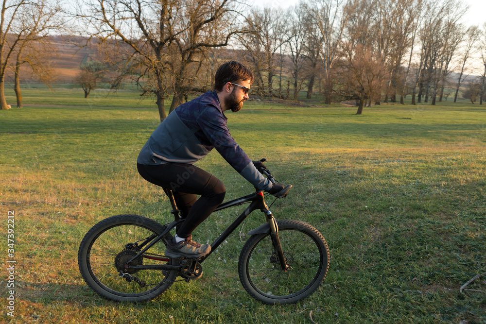 Cyclist in shorts and jersey on a modern carbon hardtail bike with an air suspension fork standing on a cliff against the background of fresh green spring forest Cyclist in shorts and jersey on a modern carbon hardtail bike with an air suspension fork standing on a cliff against the background of fresh green spring forest