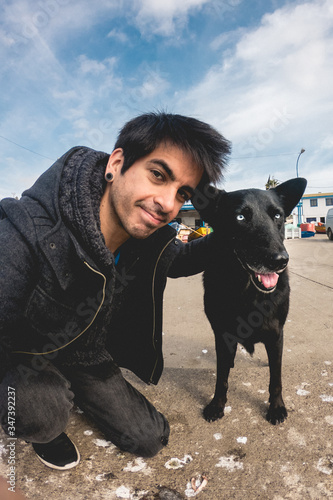 Selfie of man petting and hugging a beautiful, big and friendly black dog with white and blue eyes. Pichidangui fishermen's cove, Chile photo