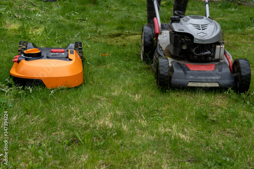 Big old and new small robot lawn mowers in the work