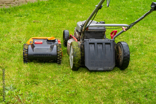 Old gas and new robot electric lawn mowers in the work