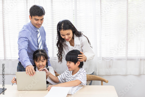 Asian parents teaching homework to kid. study online education class at home during Coronavirus or Covid-19 spreading crisis. father and mother pay attention to son and daughter. family life insurance