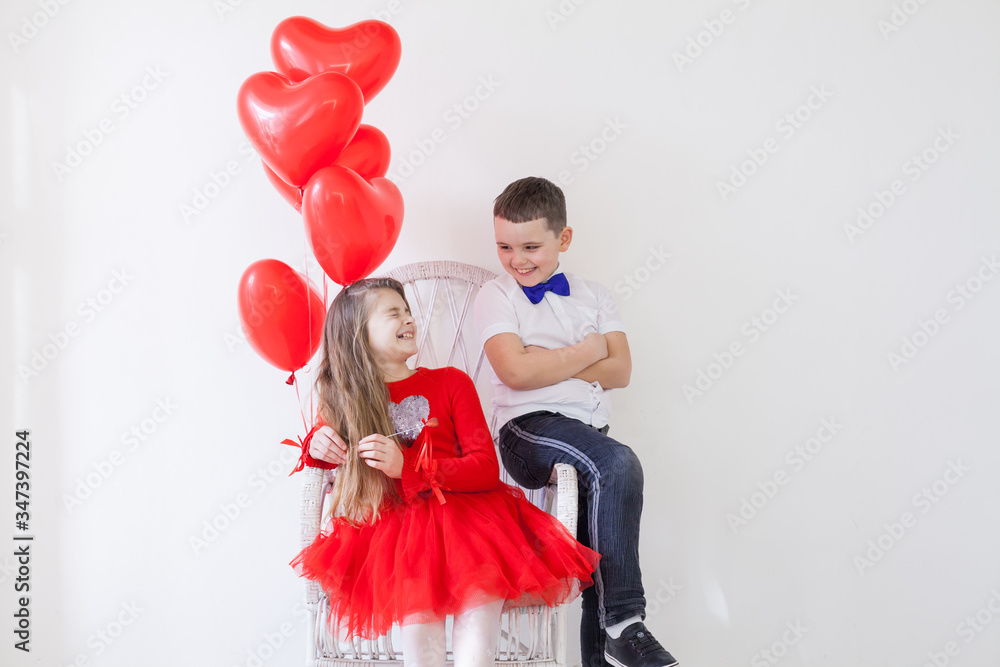 Beautiful kids friends with red balloons in the shape of a heart at the holiday Beautiful kids friends with red balloons in the shape of a heart at the holiday