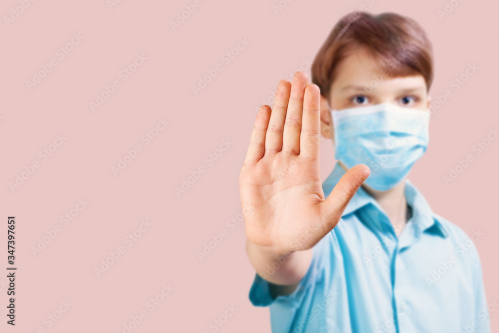 A boy in a blue medical mask with an outstretched hand in protest. Concept protection from viruses and respiratory diseases. Protecting children from COVID-19.