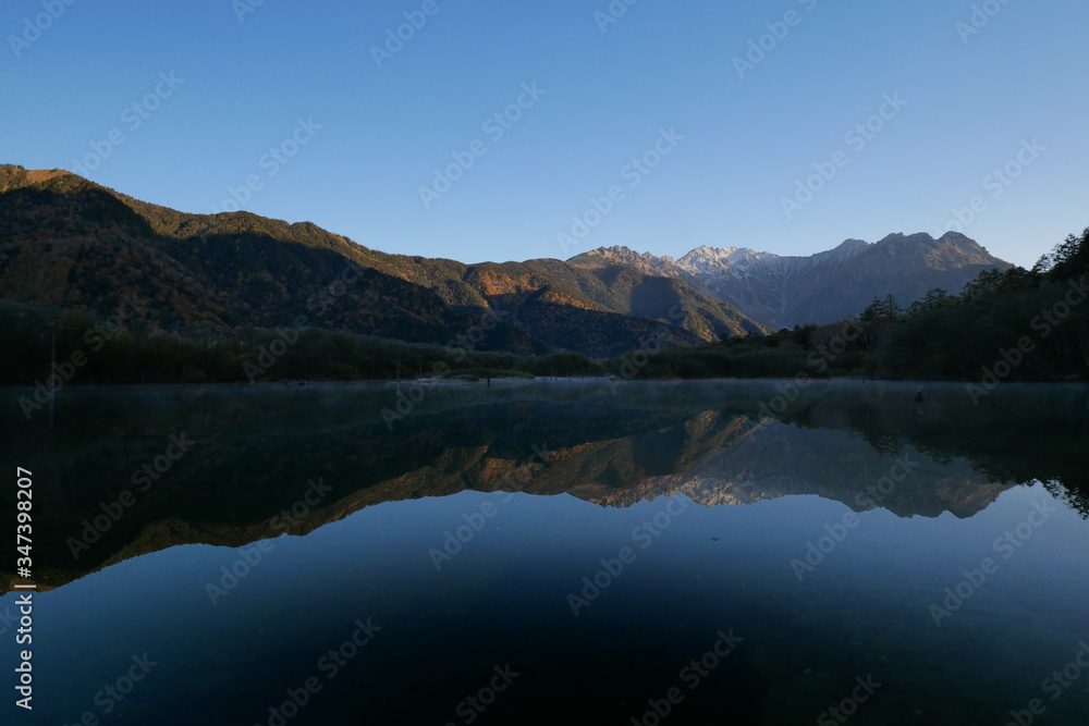紅葉の上高地・大正池から見た朝日に照らされる穂高連峰