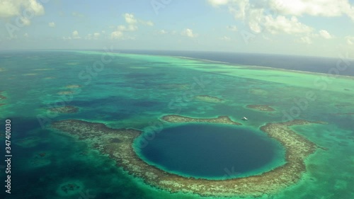 Aerial view of yacht next to marine sinkhole against cloudy sky, scenic view of seascape on sunny day - Great Blue Hole, Belize photo