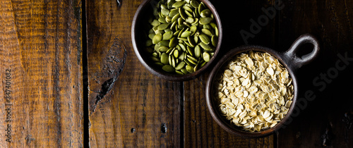 Variety of nuts, seeds and granola in a clay pots with a beautiful wooden rustic background. Healthy concept. Vegan Concept. Copy space. Top view