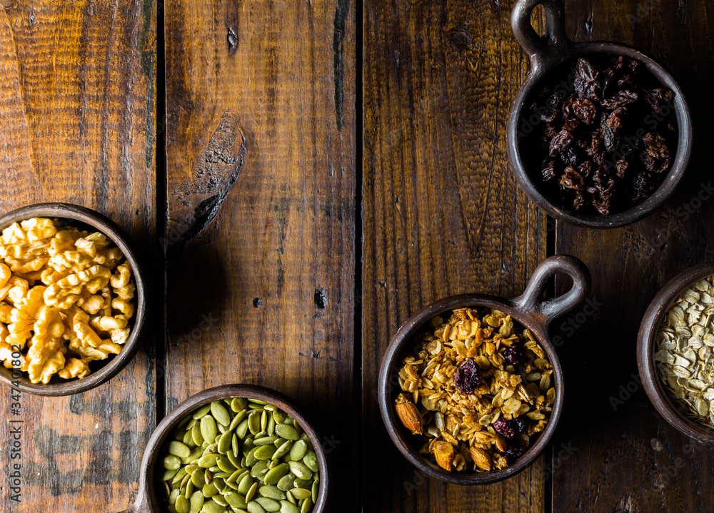 Variety of nuts, seeds and granola in a clay pots with a beautiful wooden rustic background. Healthy concept. Vegan Concept. Copy space. Top view Variety of nuts, seeds and granola in a clay pots with a beautiful wooden rustic background. Healthy concept. Vegan Concept. Copy space. Top view