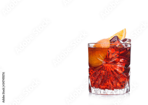 Foto Negroni Cocktail in crystal glass with ice cubes and orange slices on white background with reflection