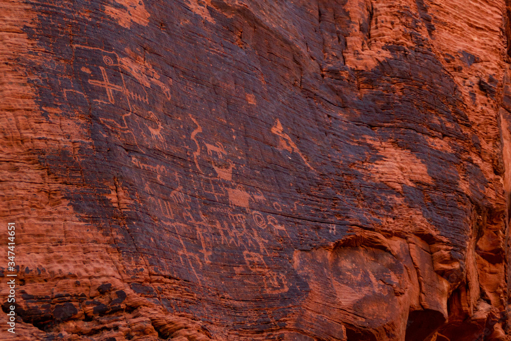 Petroglyphs of an ancient people carved on red sandstone in the Valley of Fire, Nevada, USA. Glyph symbols as means of communication by prehistorical desert tribes. Cave paintings of native people