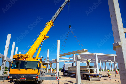 Unloading concrete pillar from truck trailer at construction site