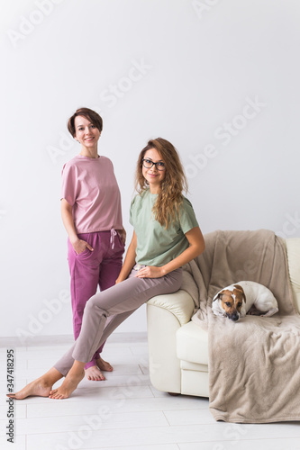 Two female friends or sisters at home with their cute dog. Quarantine  isolation  coronavirus pandemic world. Stay at home.