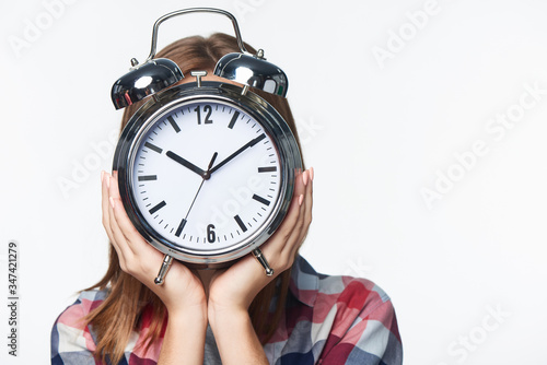 Smiling teen girl holding alarm clock in front of her face