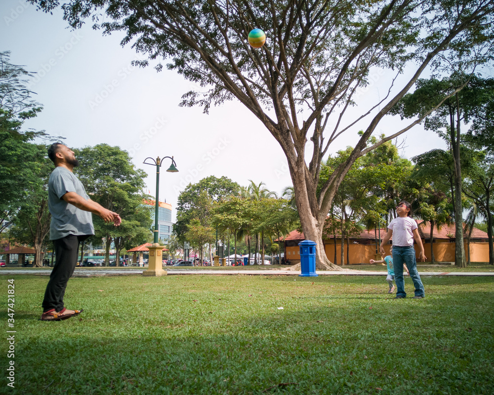 Fototapeta premium Family of three playing ball in the Malaysia park.