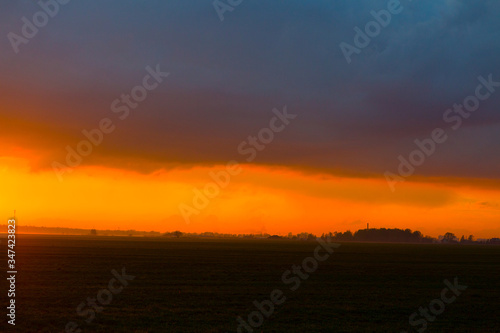 Sunset on the field. Beautiful sunset landscape with large field and a forest on background