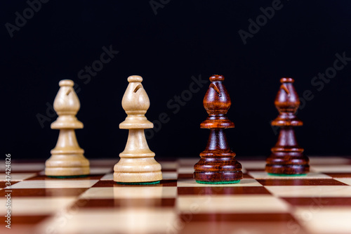 four chess bishops on a chessboard on a black background