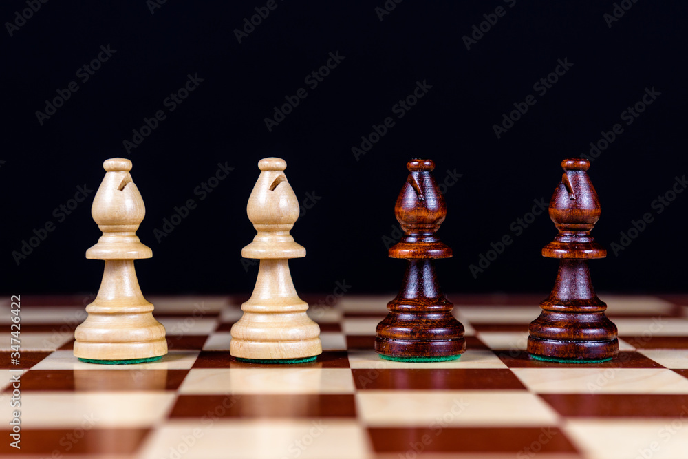 four chess bishops on a chessboard on a black background four chess bishops on a chessboard on a black background