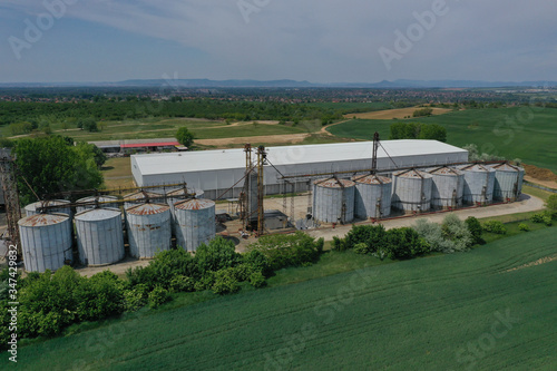 Aerial view with drone, agricultural silo, next to wheat or barley field - industrial elevator dryers, building exterior, storage and drying of cereals, wheat, corn, soybeans, sunflowers. In Europe