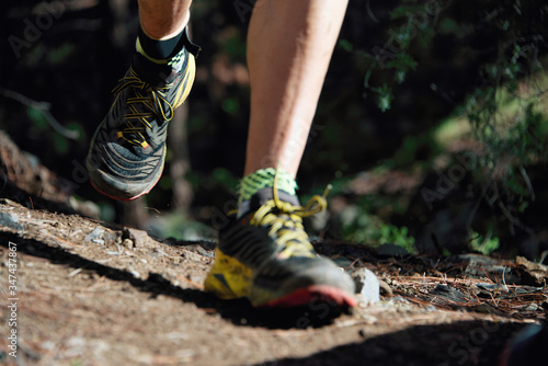 Trail running workout outdoors on rocky terrain  sports shoes detail on a challenging forest track