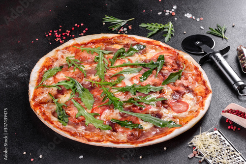 Fresh pizza baked in oven with arugula, salami, cherry tomatoes and mozzarella