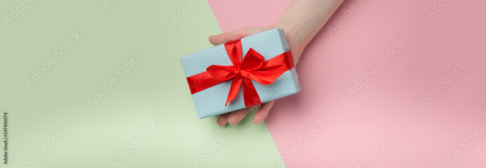 Woman holds a white gift box with a red bow on a colored background. Gift for birthday, Christmas, Valentine's Day, New year . Flat lay Woman holds a white gift box with a red bow on a colored background. Gift for birthday, Christmas, Valentine's Day, New year . Flat lay