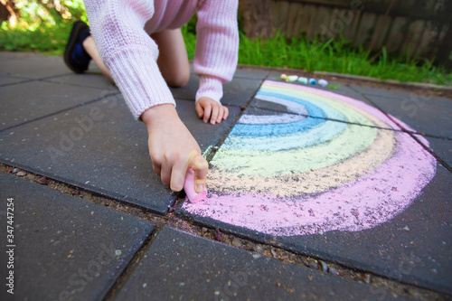 Wide angle view of girl drawing rainbow with shallow focus