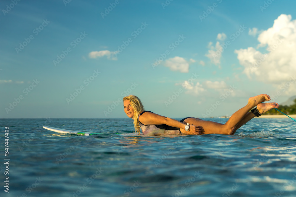 A beautiful girl rowing on a surfboard in the ocean
