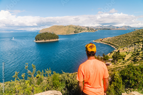 Tourist MAN on Island at Isla del Sol in Bolivia. Scenic panoramic view of island and sea horizon. Bolivian island paradise and hills. Walking trail, by boat. Local community, tourism. Titicaca lake © Jam Travels