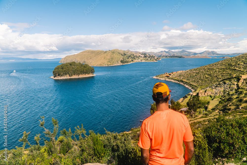 Tourist MAN on Island at Isla del Sol in Bolivia. Scenic panoramic view of island and sea horizon. Bolivian island paradise and hills. Walking trail, by boat. Local community, tourism. Titicaca lake