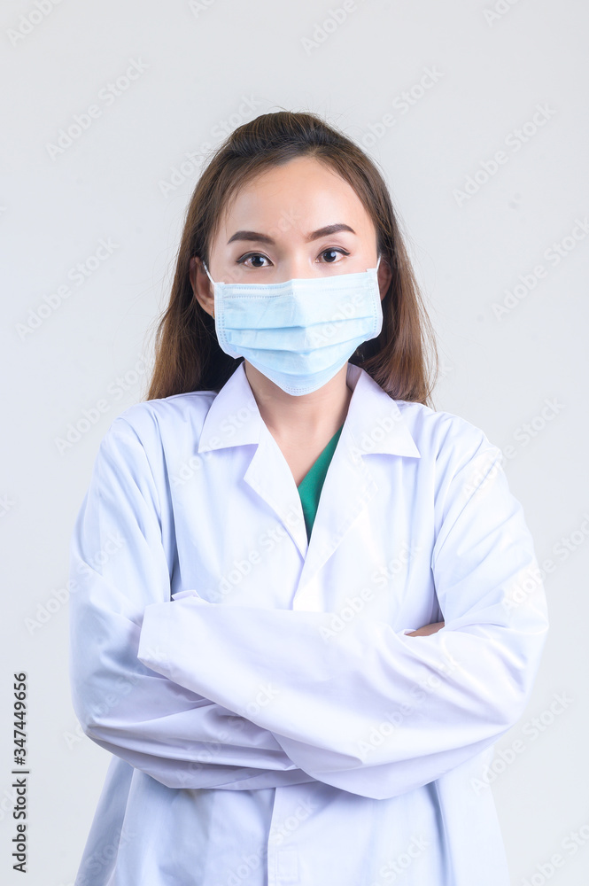 A beautiful Asian surgeon dressed in a green surgical gown wearing a mask is standing and crossed her arms. A beautiful Asian surgeon dressed in a green surgical gown wearing a mask is standing and crossed her arms.