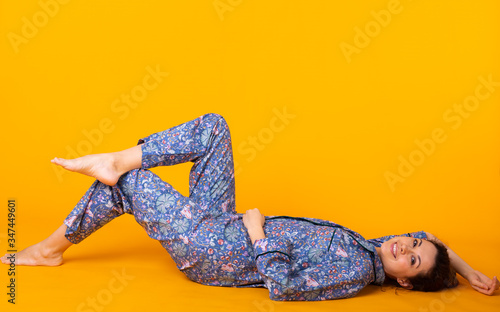 Close up young woman in blue home wear. Isolated on yellow background.