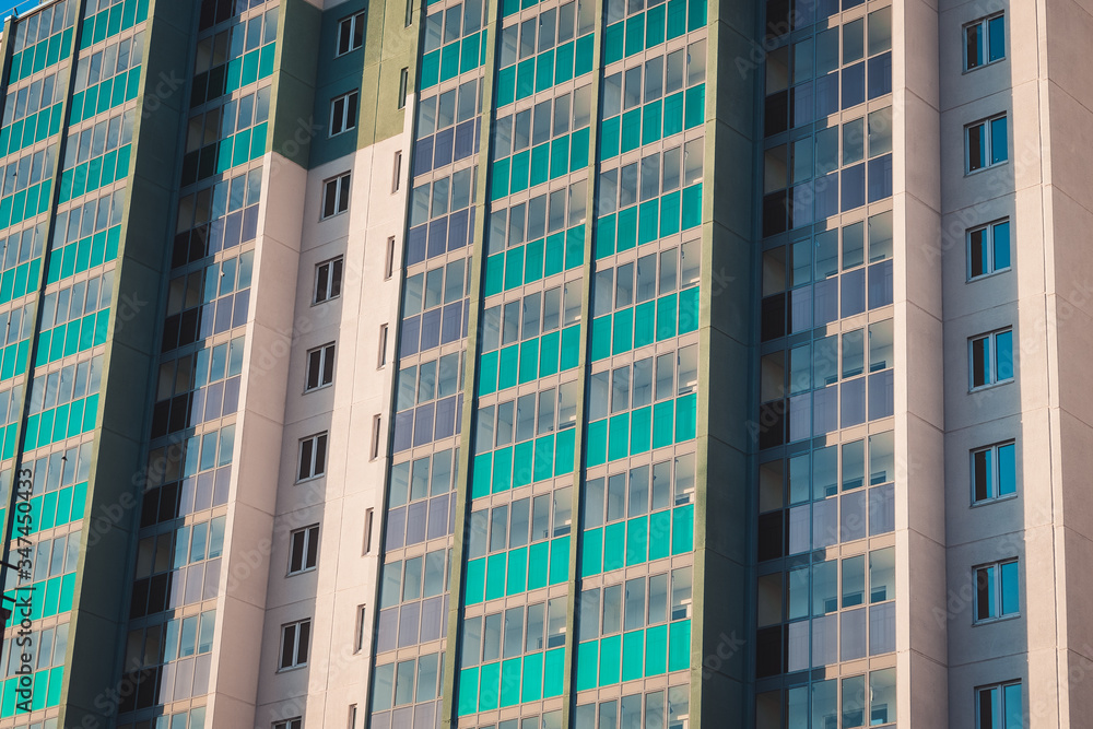 Close-up - part of new multistorey panel home with balconies and windows, new building in sunlight.